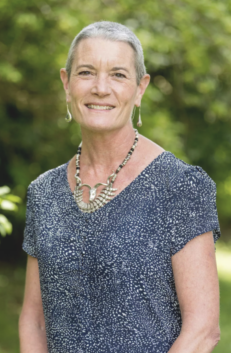 Headshot of Theresa Burriss standing outside and smiling while wearing a blue and white printed top