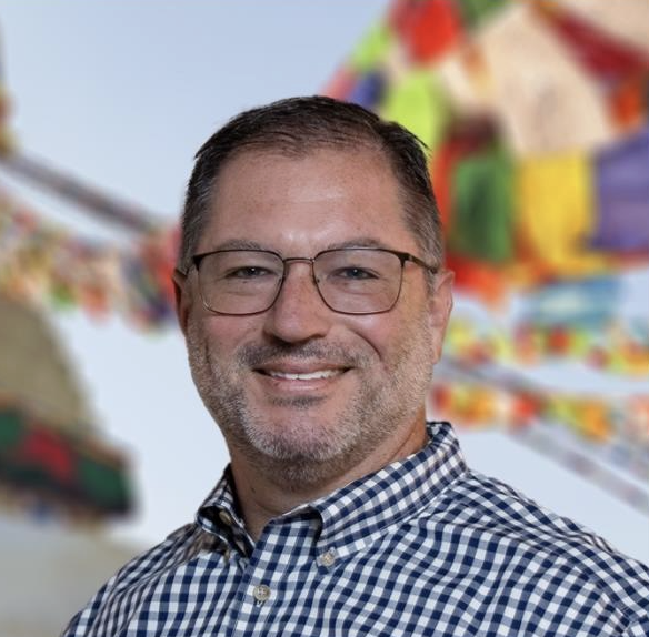 Headshot of David Rettinger smiling while wearing a blue and white gingham check shirt
